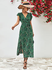 Model wearing a green printed surplice dress with flutter sleeves, front view and straw hat.