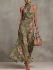 Model wearing a green floral sleeveless maxi dress with a flowing tiered skirt.