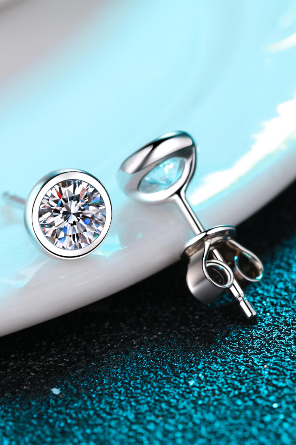 Round clear-stone stud and post back shown on a teal surface
