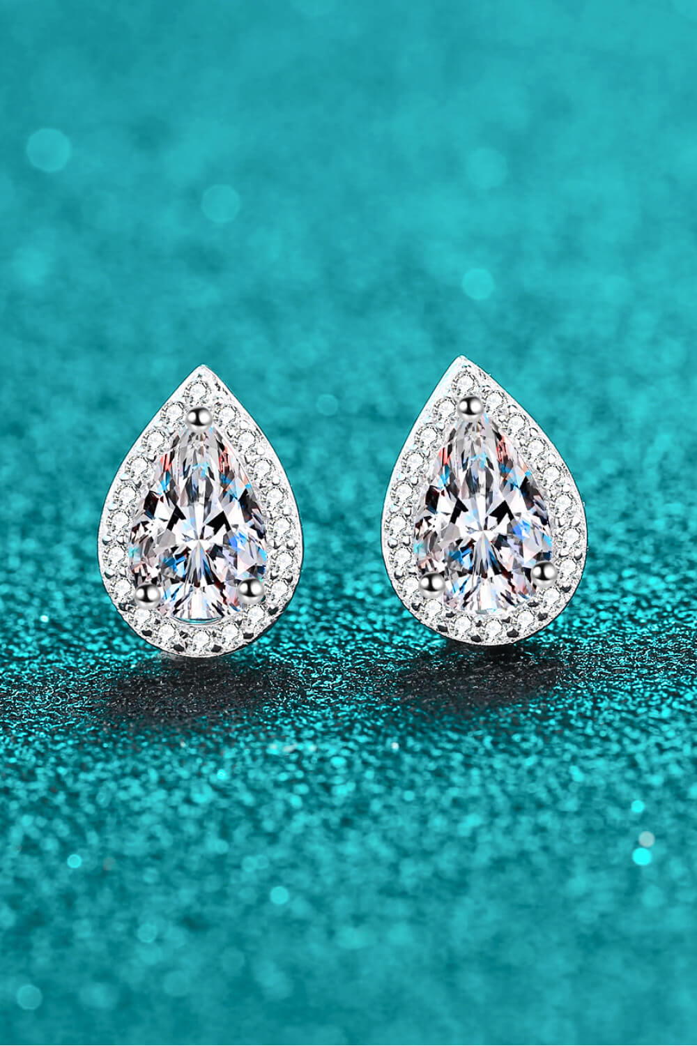 Pair of teardrop stone studs on a teal textured surface