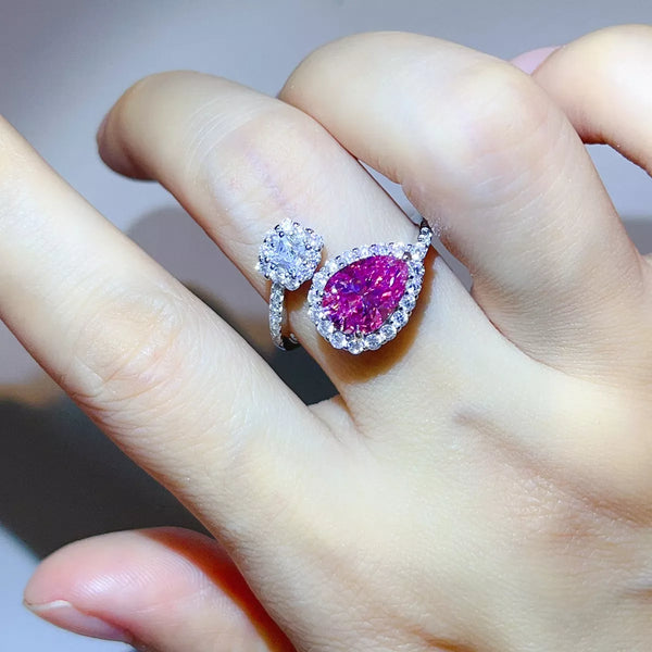 Pink pear-shaped bypass ring with clear-stone cluster worn on hand