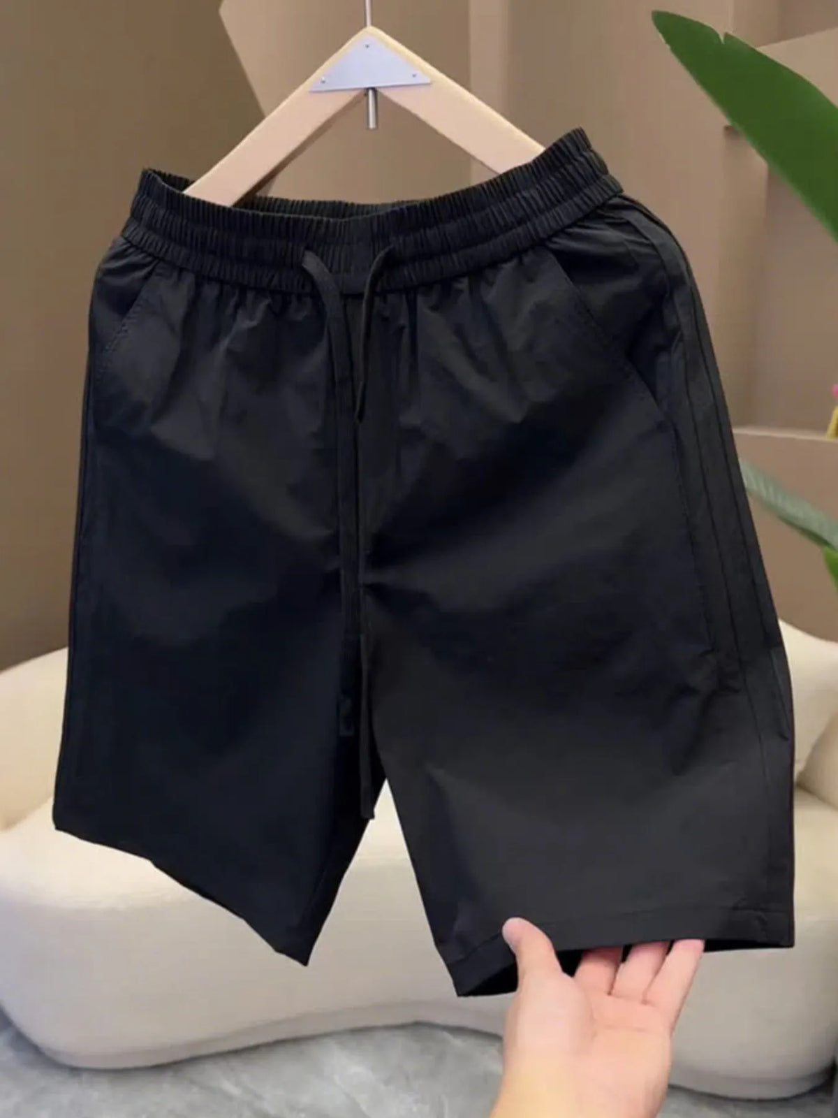 Black pocketed drawstring shorts hanging on a hanger