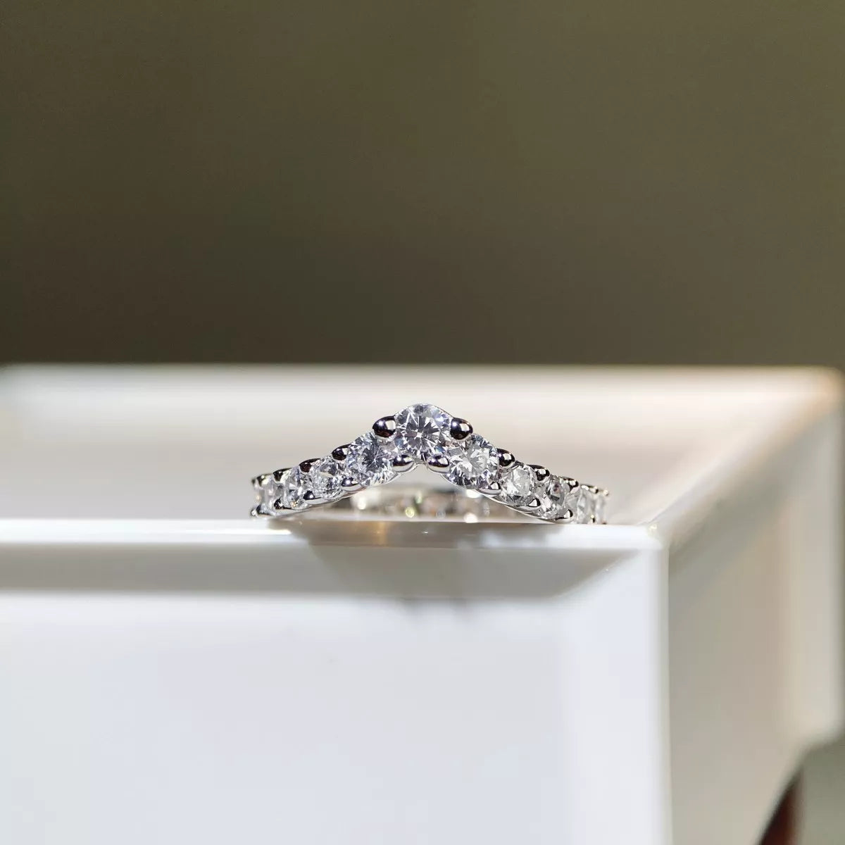 V-shaped ring displayed from the front on a light surface.
