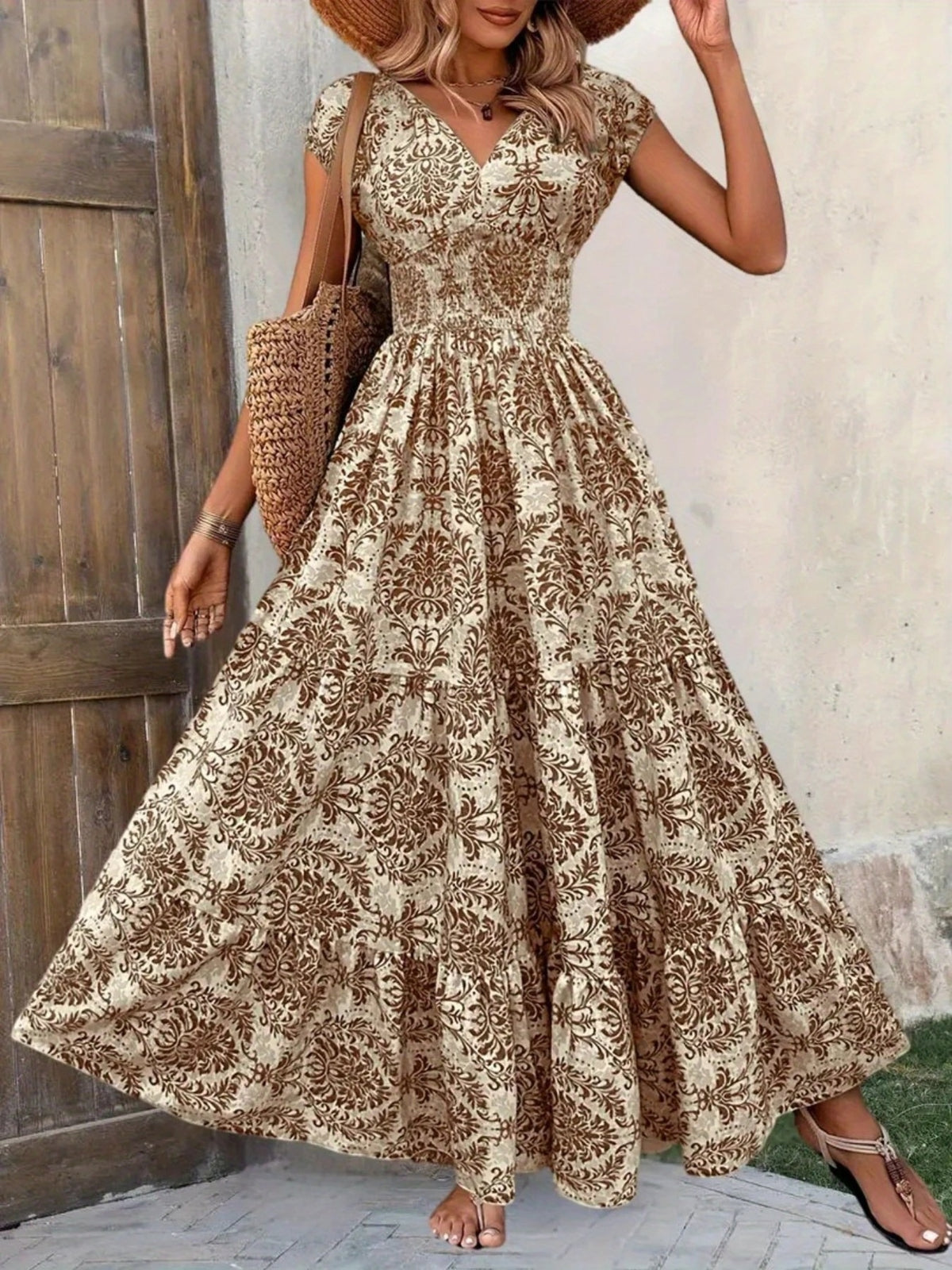 Front view of brown floral cap-sleeve maxi dress with a smocked waist and widely flared tiered skirt.