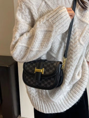 Black patterned flap bag worn on a long black strap with gold-coloured attachments