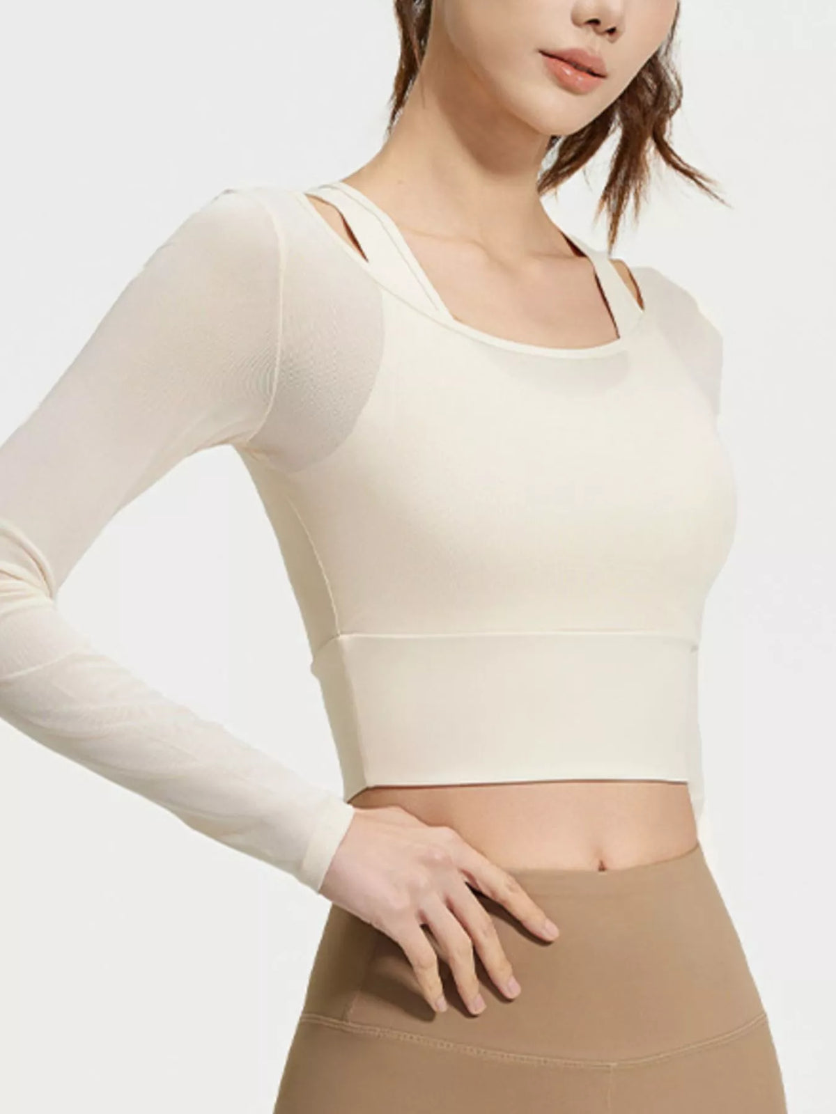 Model wearing cream layered active top with one hand on the hip above tan leggings