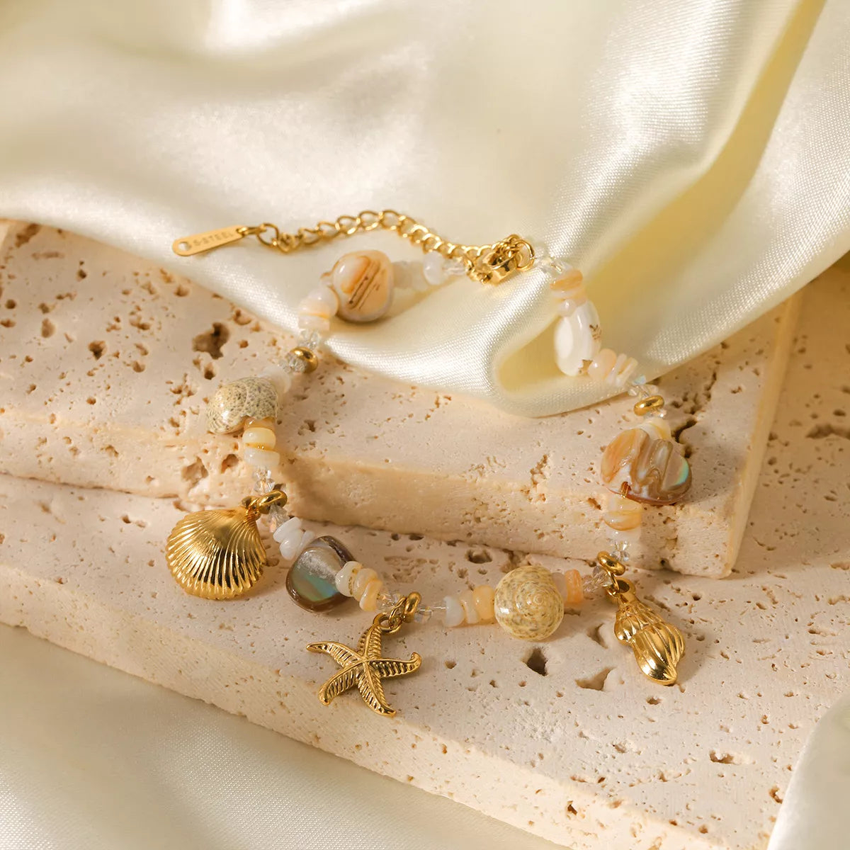 Gold bracelet with shell charm worn on wrist