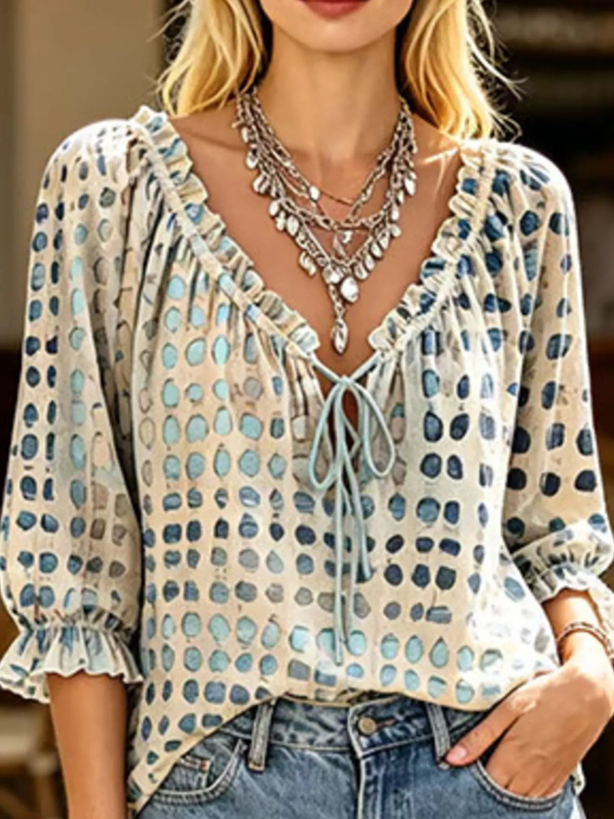 Model in beige spotted tie-neck blouse with ruffled three-quarter sleeves and jeans