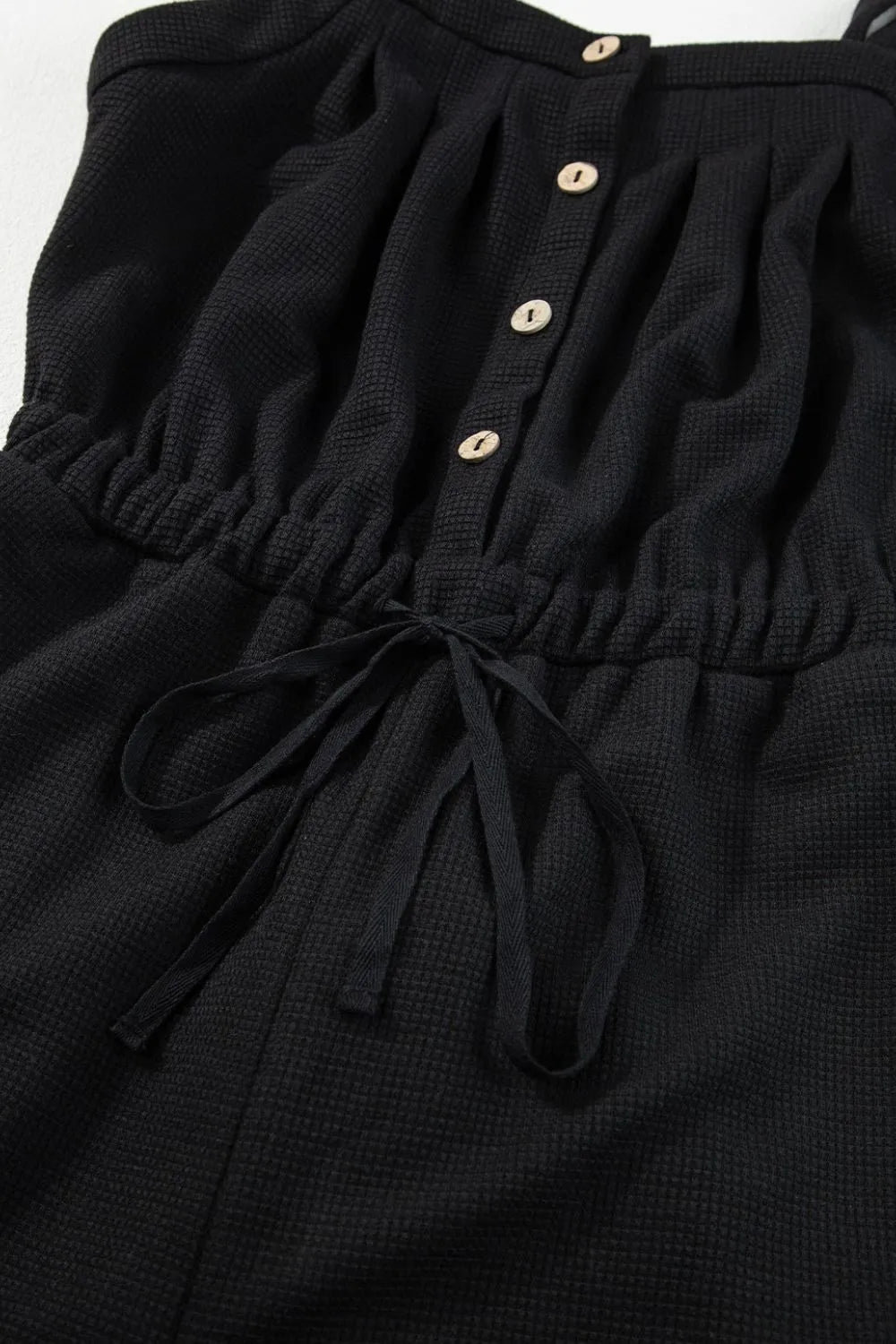 Black jumpsuit waist showing elastic gathering and drawstring tie