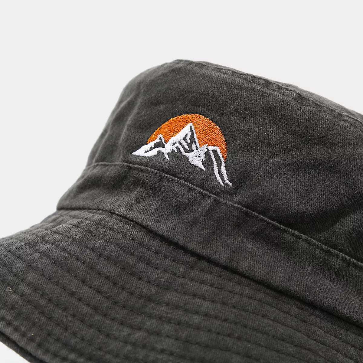 Close view of orange sun and white mountain embroidery on black hat