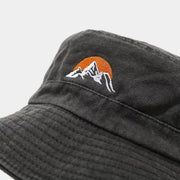 Close view of orange sun and white mountain embroidery on black hat