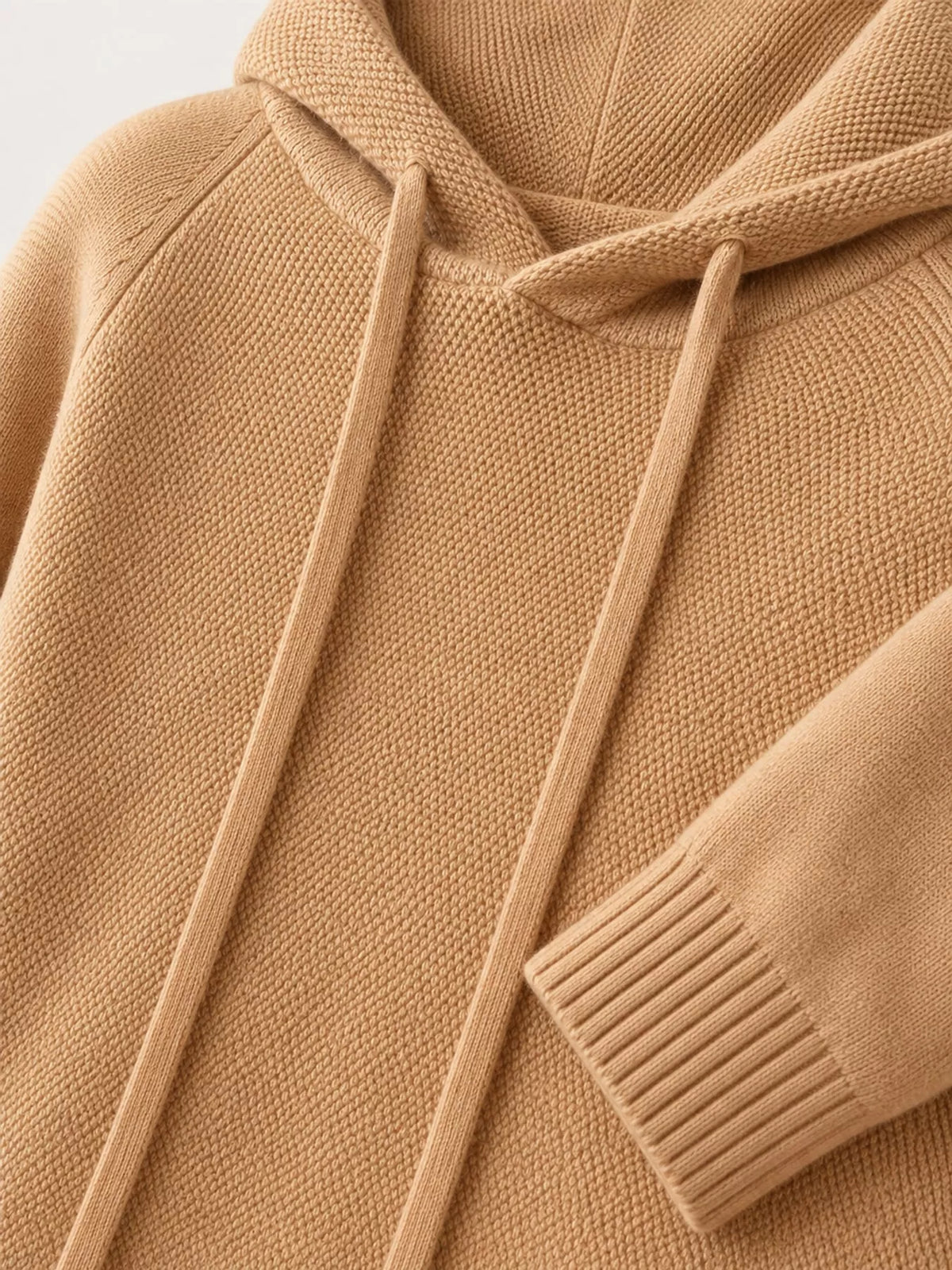 Camel sweater close-up showing the hood opening, long drawstrings and ribbed cuff.
