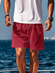 Man wearing red drawstring shorts by the water