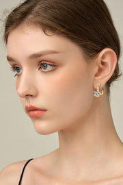 Model wearing gold-tone round-stone drop earrings in a side portrait