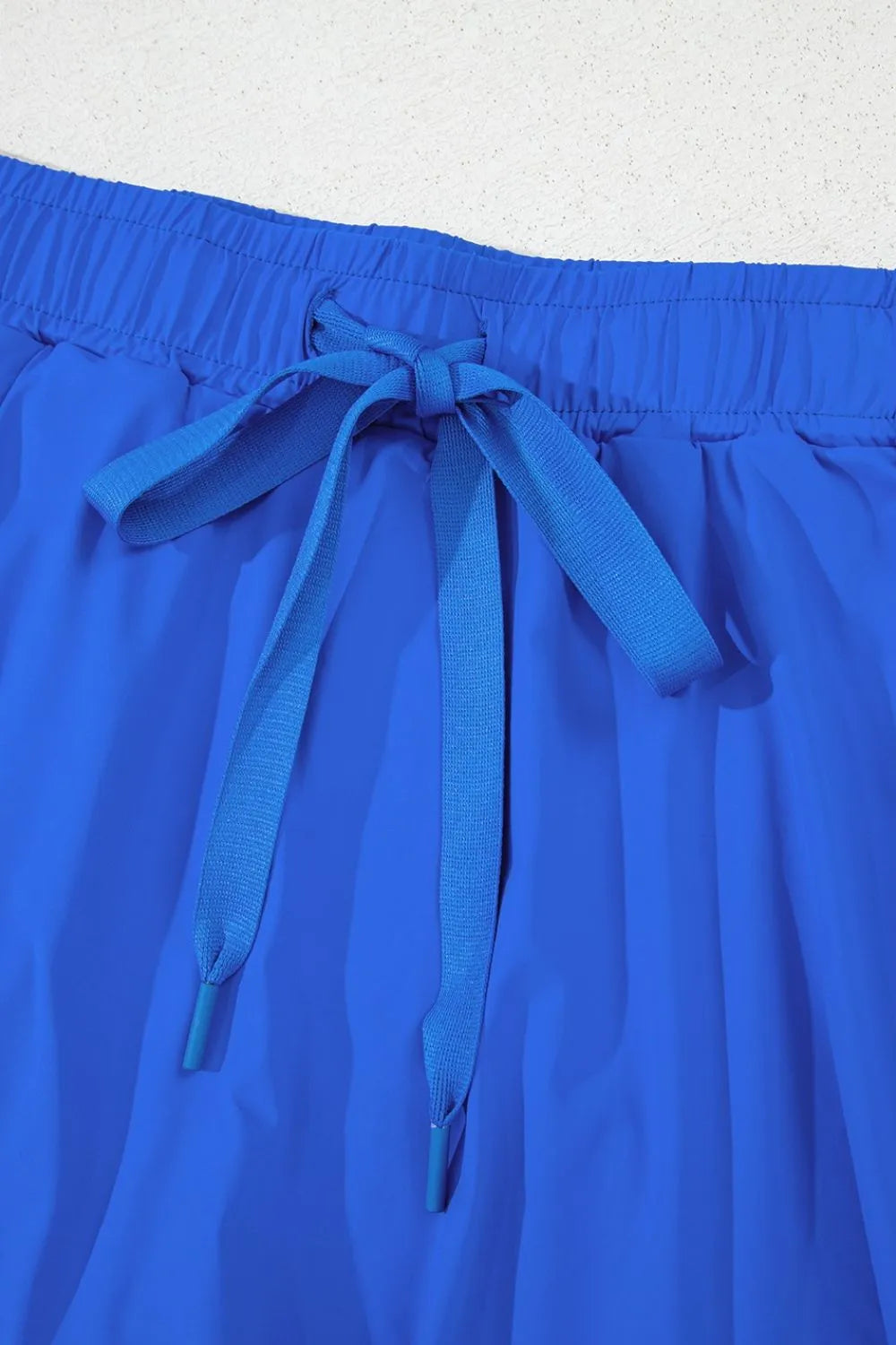 Detail of blue skort waistband with tied drawstring and layered front skirt