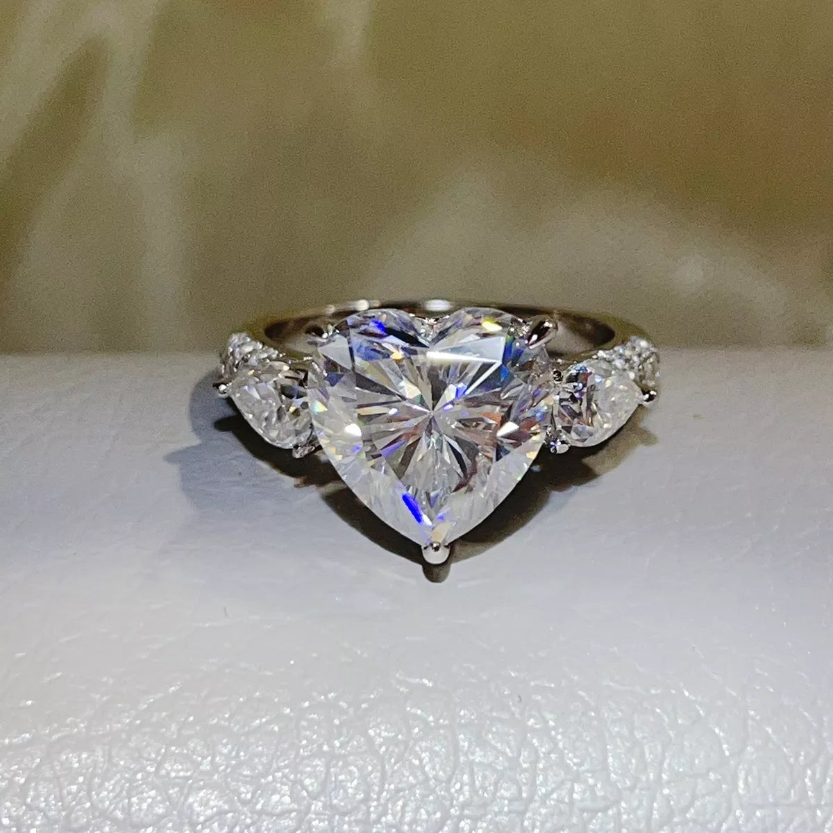 Clear heart-shaped moissanite ring displayed on a light surface.