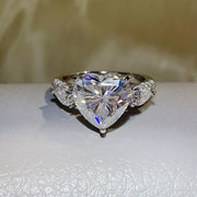 Clear heart-shaped moissanite ring displayed on a light surface.