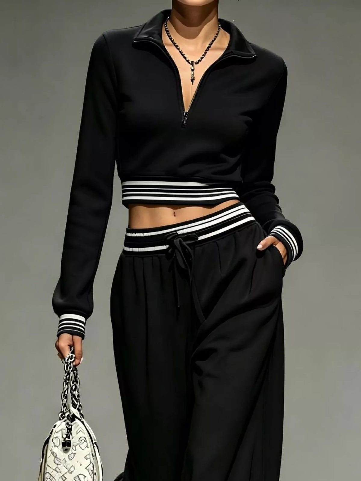Closer view of black half-zip crop top, striped trim and drawstring pants