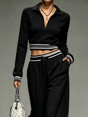 Closer view of black half-zip crop top, striped trim and drawstring pants