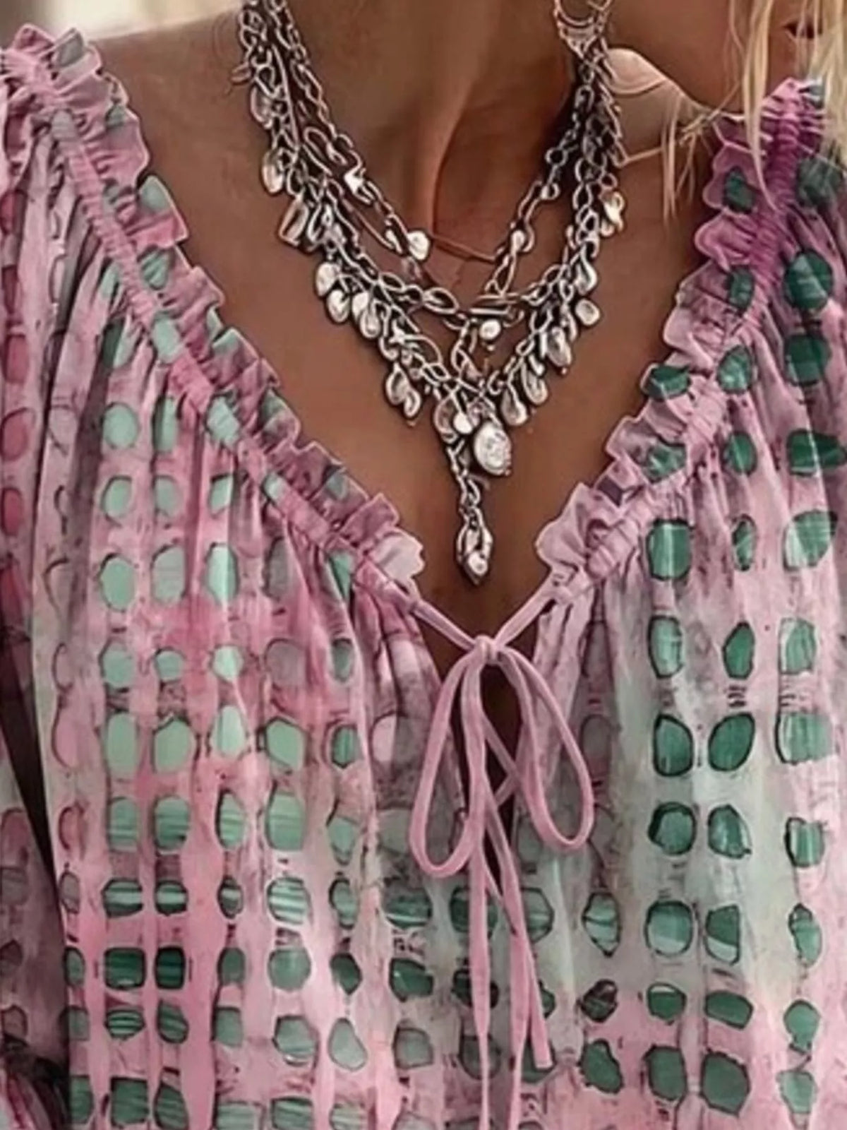 Close-up of the pink blouse's ruffled V-neckline and bow ties.