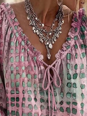 Close-up of the pink blouse's ruffled V-neckline and bow ties.
