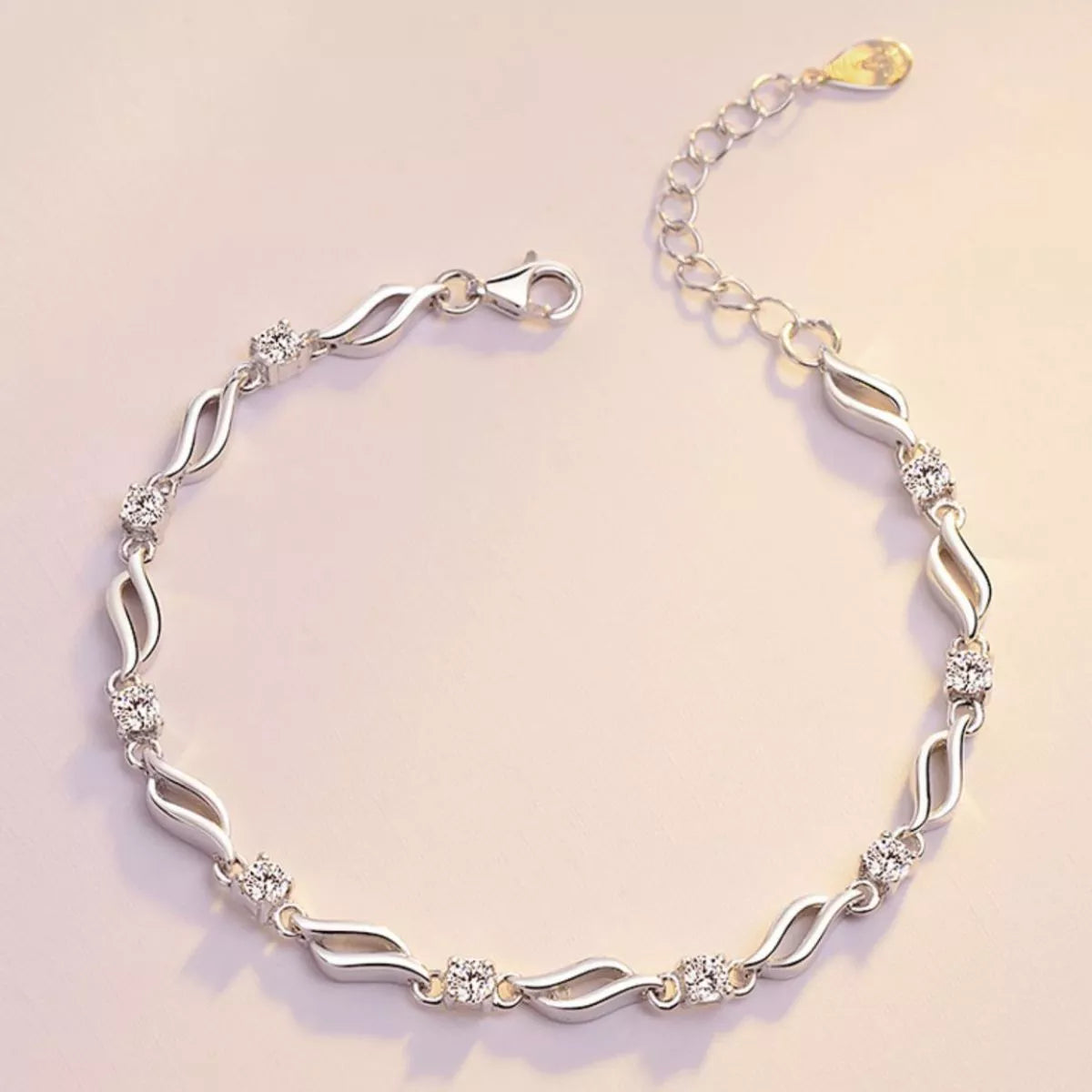 Full view of a silver-tone wavy-link bracelet with floral zircon details and clasp
