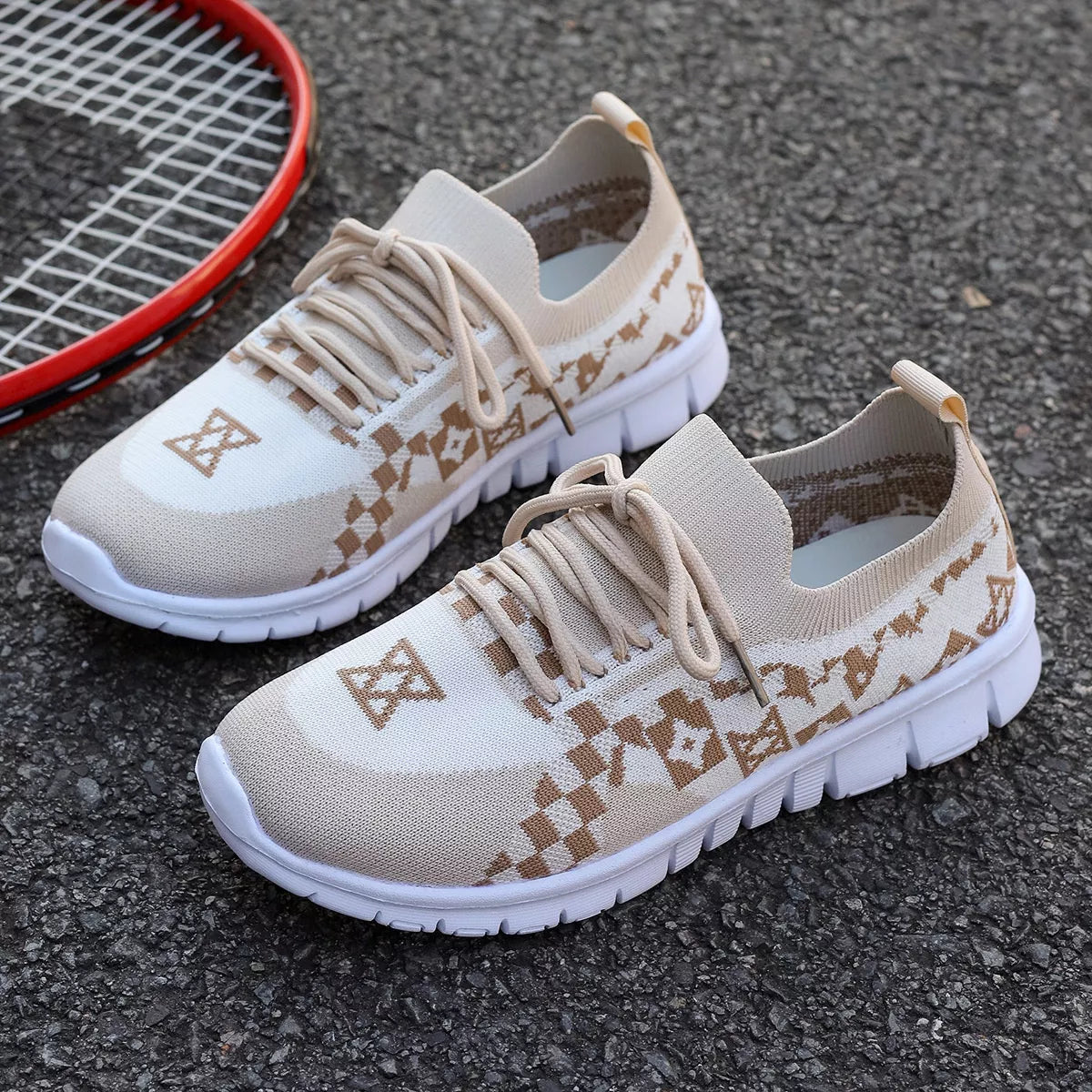 Cream mesh sneaker with tan patterned panels, top view beside a tennis racket