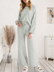 Model wearing light gray V-neck lounge top and matching wide-leg pants