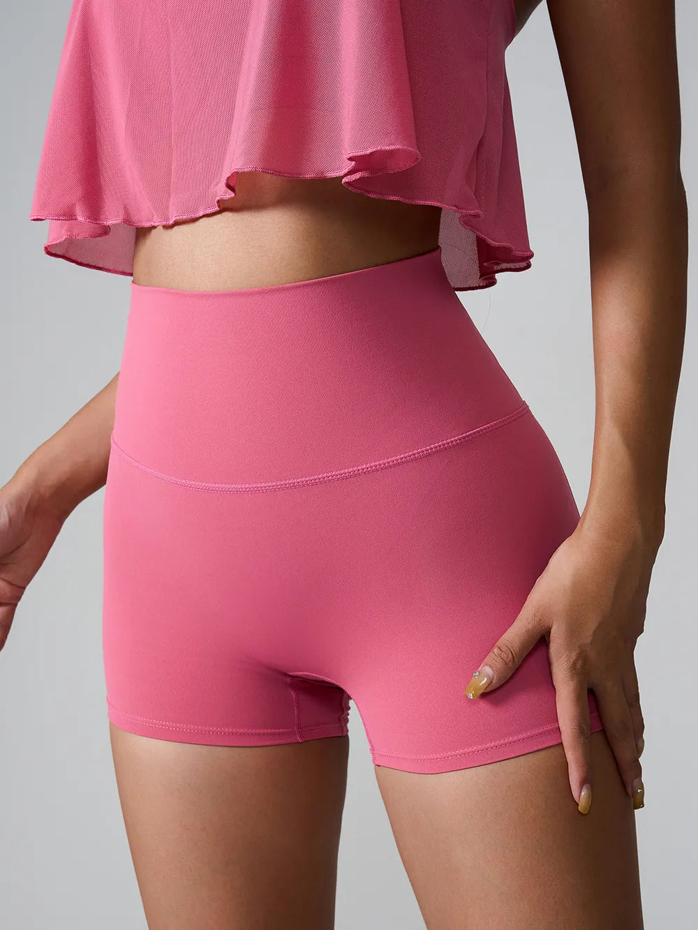 Front view of bright pink fitted shorts worn under a flowy top.