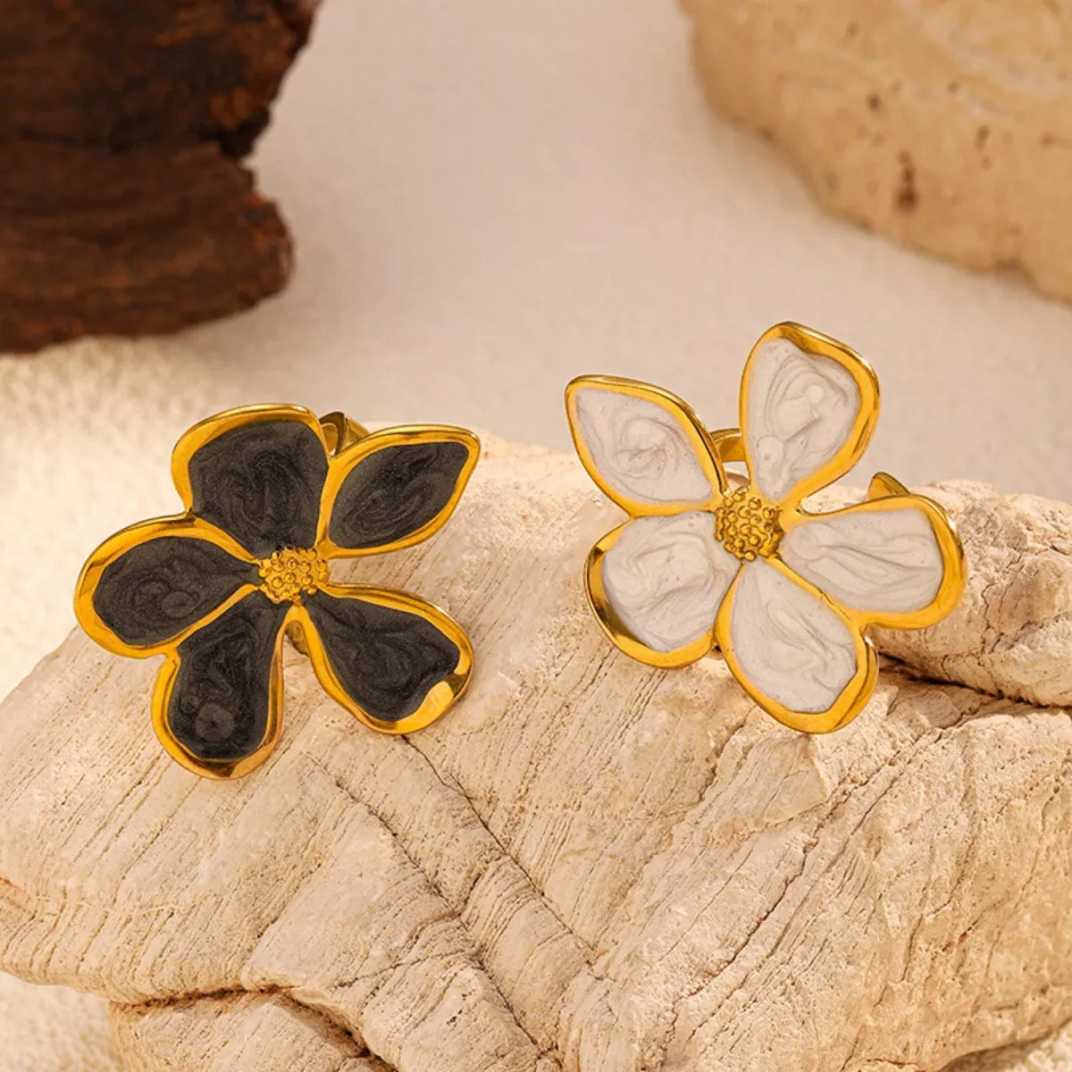 Gold-tone open flower rings with black and white petals displayed together
