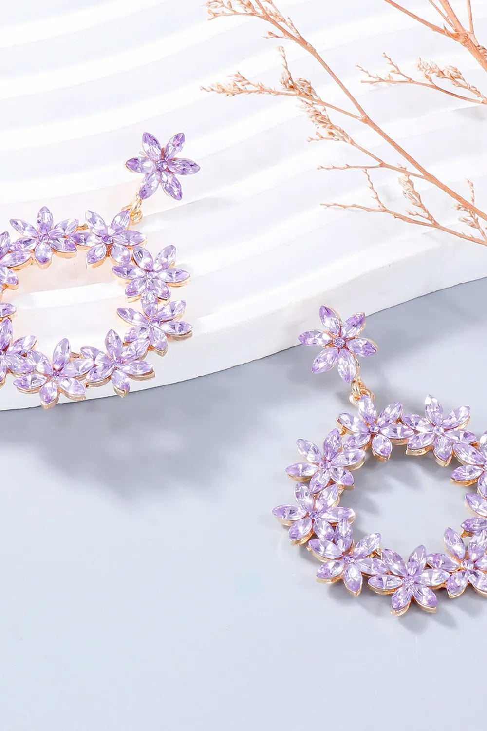 Lavender rhinestone flower dangle earring displayed on white