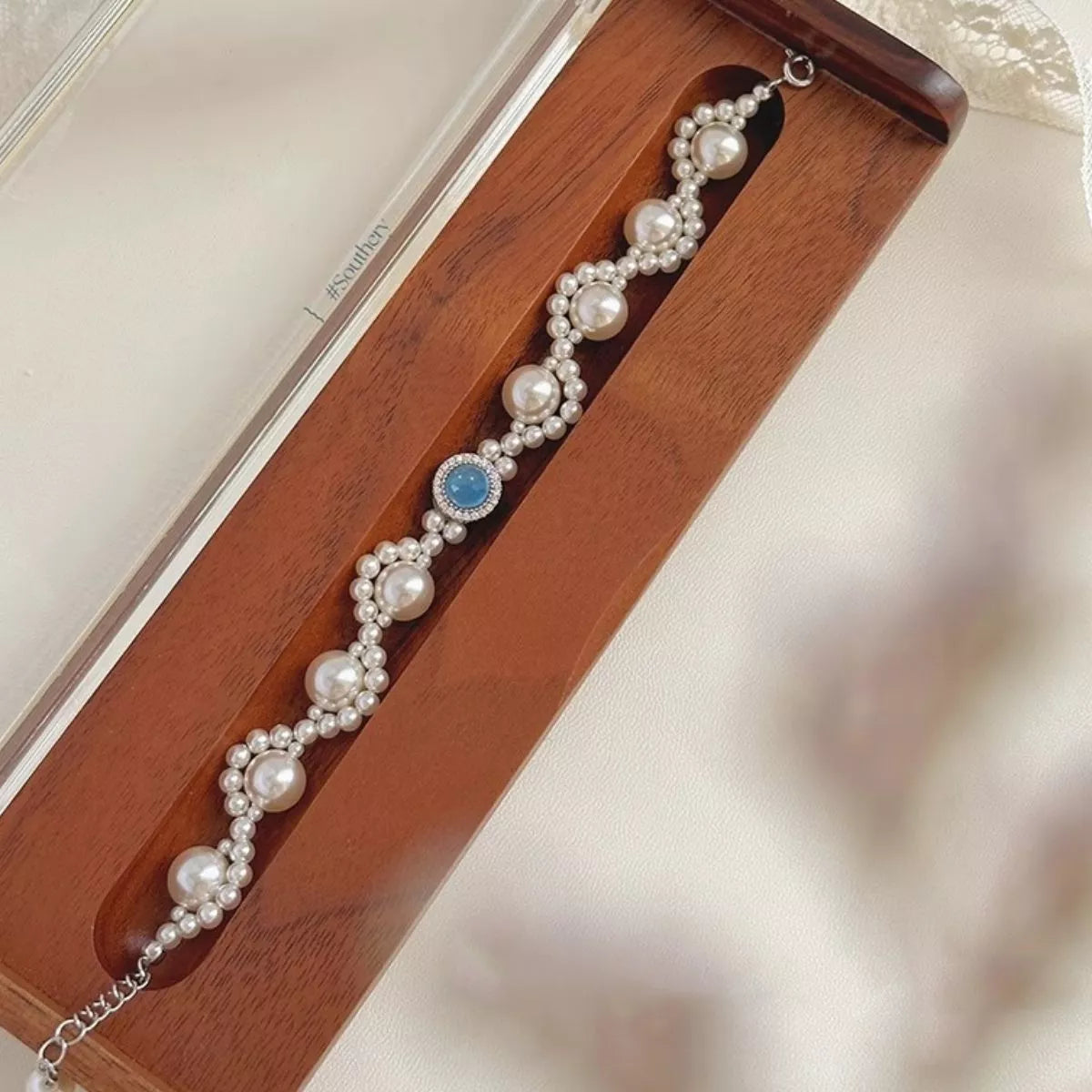 Pearl bracelet with blue center stone arranged in a presentation box