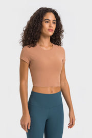 Model in peach cropped T-shirt and teal leggings, three-quarter view
