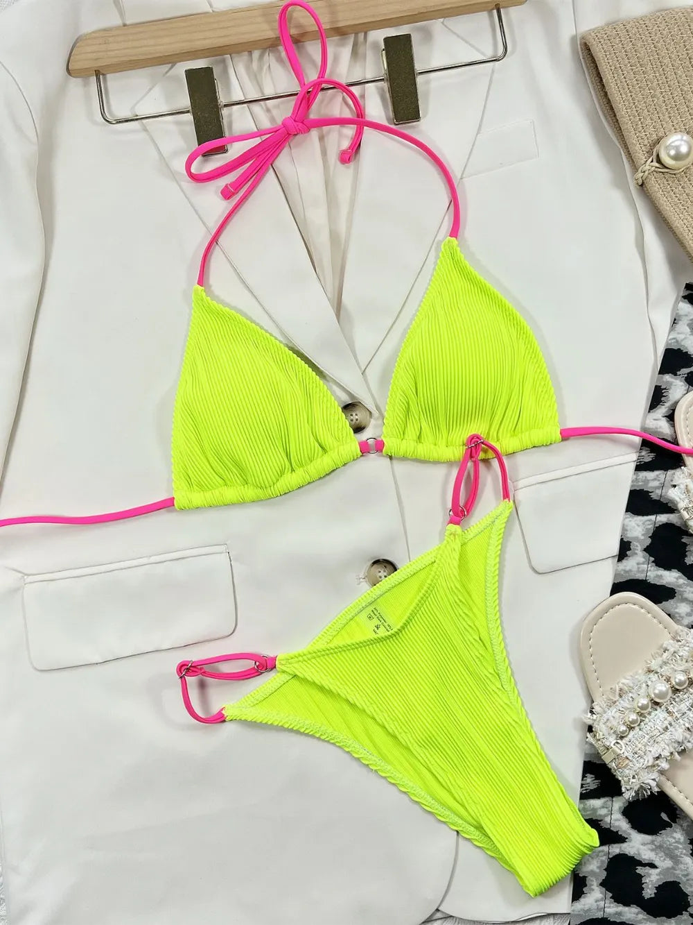Neon yellow ribbed bikini top and bottoms with pink straps laid flat on a white jacket