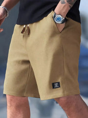 Front view of tan waffle-knit shorts with drawstring waist and small black hem label