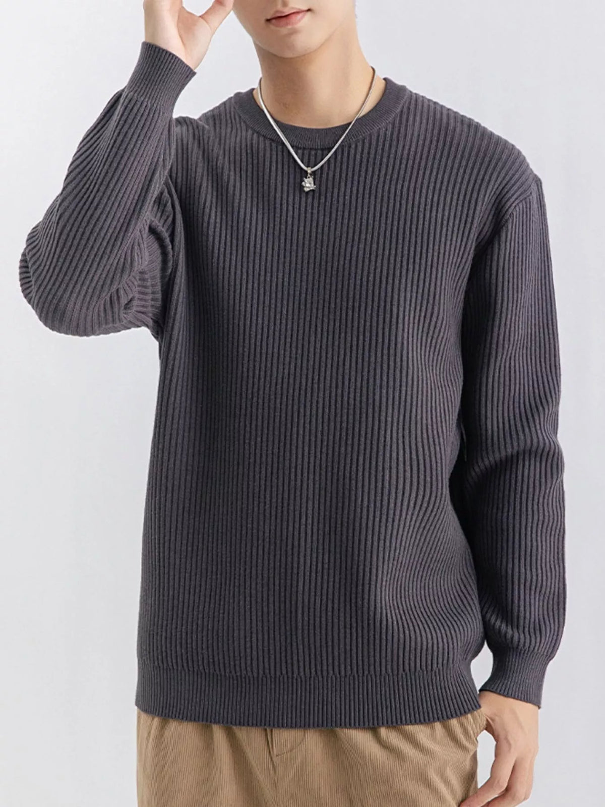 Model wearing charcoal grey ribbed crew-neck sweater with one hand raised