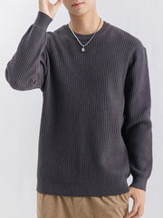 Model wearing charcoal grey ribbed crew-neck sweater with one hand raised