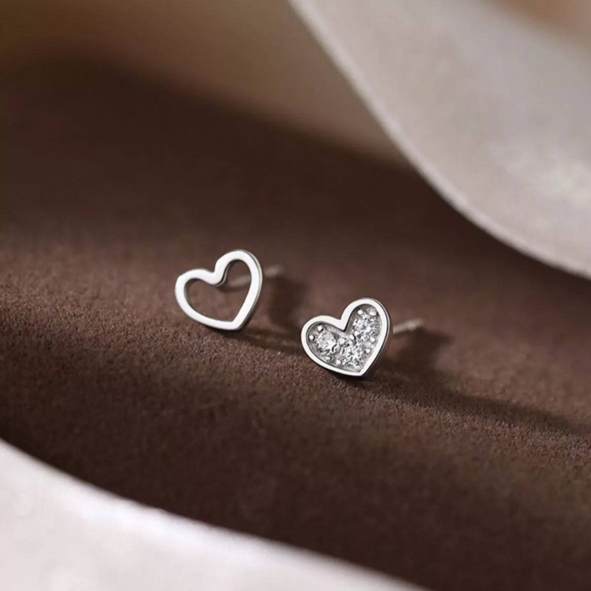 Pair of heart stud earrings with one pavé heart and one open heart