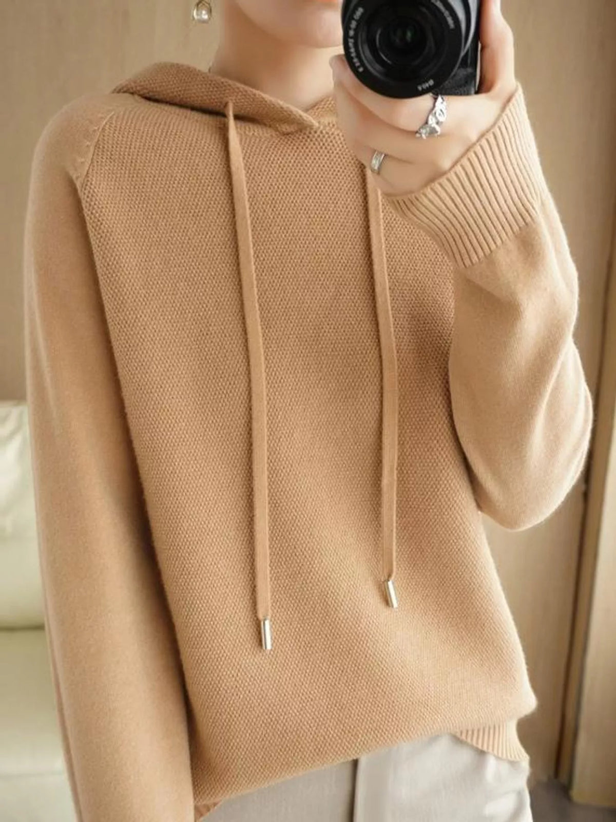 Light tan hooded sweater shown in a front mirror photo with a hand holding the camera.