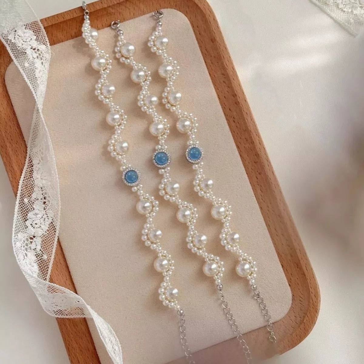Three pearl bracelets with blue center stones displayed in a tray