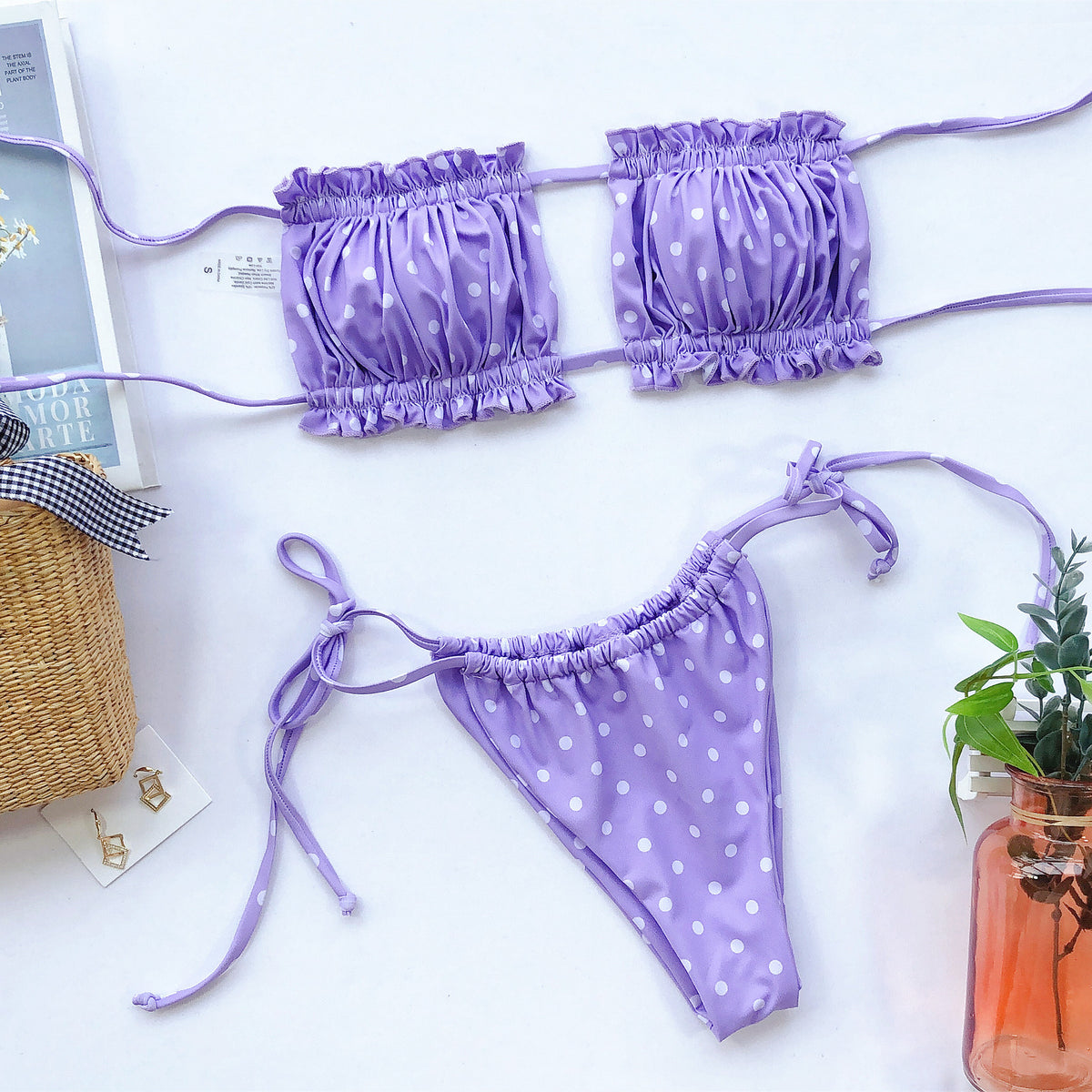 Lavender polka-dot ruched bikini top and tie-side briefs laid flat on white