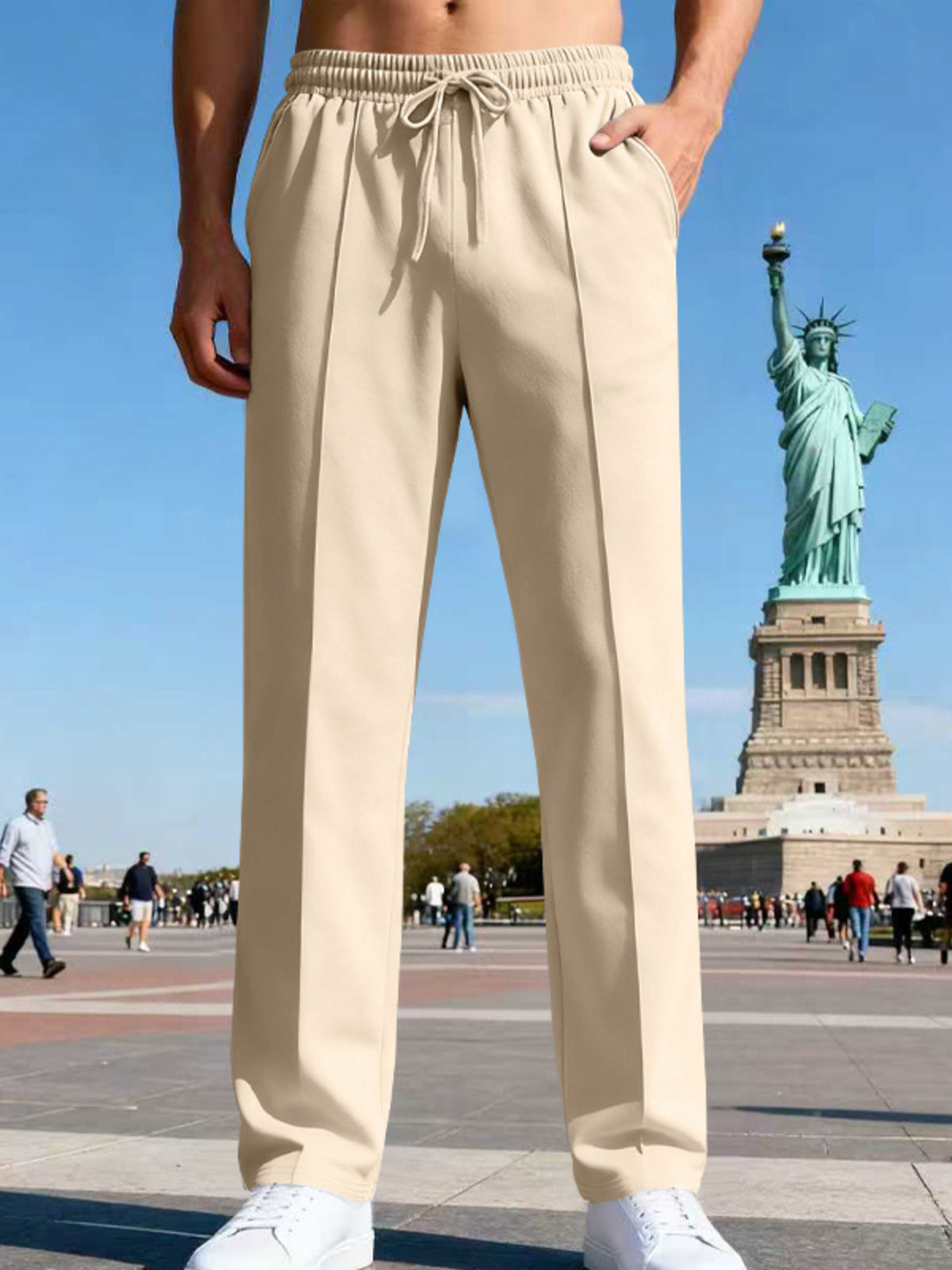 Front view of cream straight-leg pants with elastic drawstring waist near the Statue of Liberty.