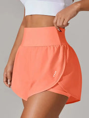 Coral high-waisted running shorts with overlapping front panel, close view