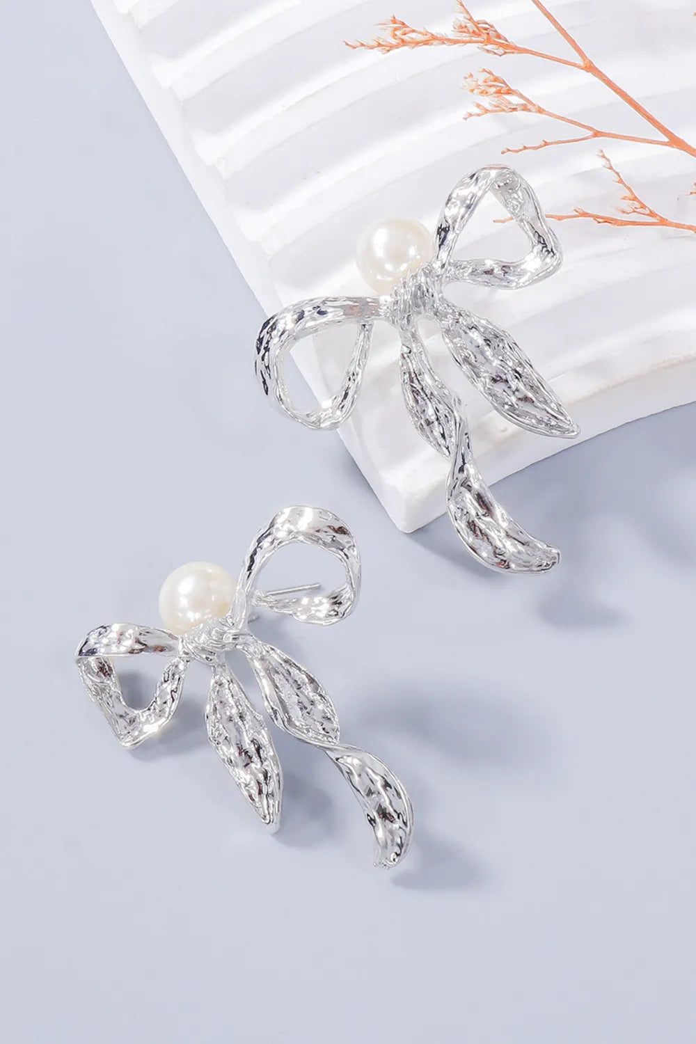 Angled close-up of silver-tone bow earrings showing their posts
