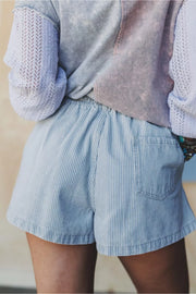 Back and side view of light blue striped shorts on a model.