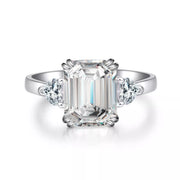 Front view of white-metal ring with emerald-cut clear center stone and two side stones