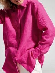 Close-up of bright pink gauze shirt with gathered sleeve cuff.