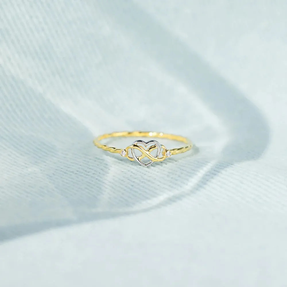 Infinity-heart ring displayed on pale blue fabric