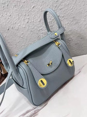 Angled front view of a blue pebbled crossbody bag with gold-tone hardware