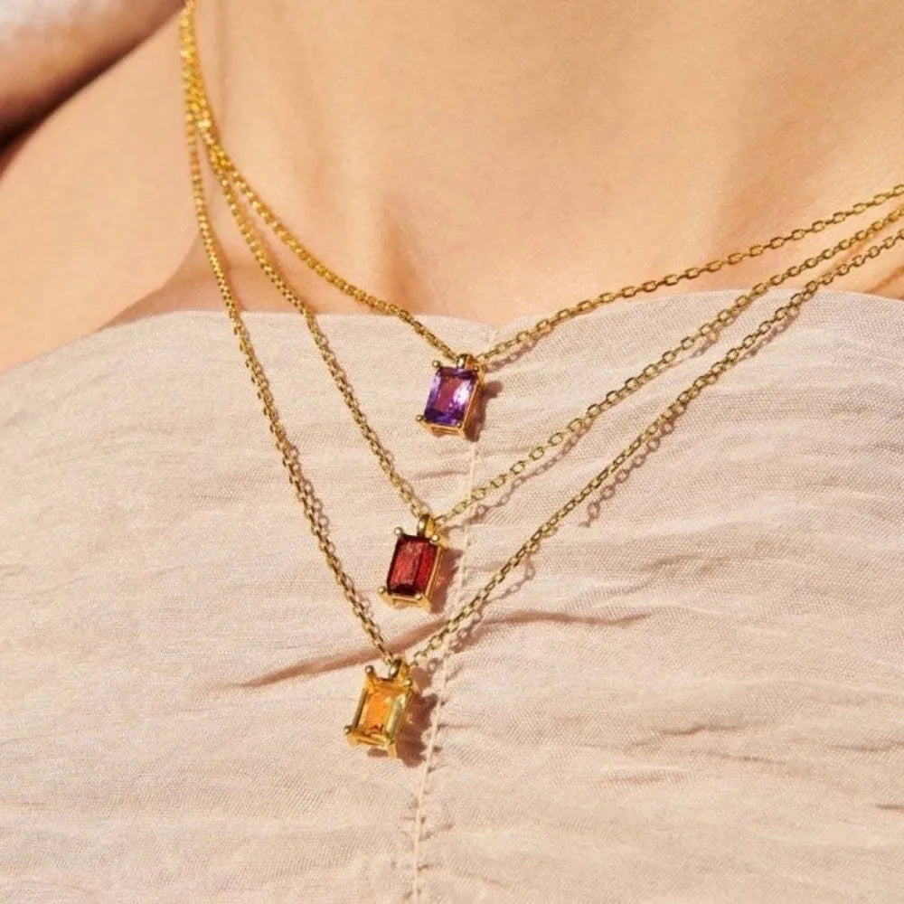 Three layered gold-tone necklaces with purple, red and amber rectangular pendants